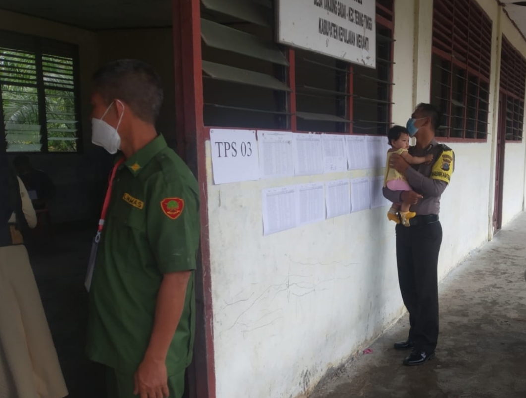 Polisi di Kepulauan Meranti Bantu Gendong Bayi Saat Ibunya Nyoblos Pilkades di TPS